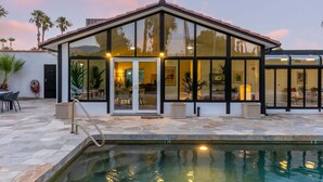Une maison moderne dotée d’une piscine, de grandes baies vitrées et d’une terrasse en pierre.