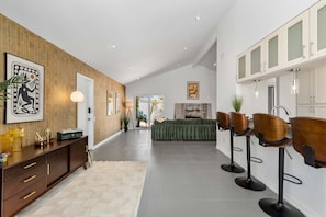 Ein modernes Interieur mit einer Holzverkleidung, einem grünen Sofa und einer Bar mit Hockern.