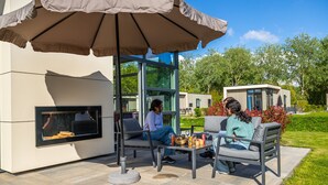 Un espace extérieur aménagé avec une table et des chaises, un grand parasol et une cheminée intégrée.