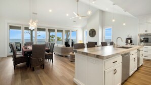 A spacious kitchen with a large island, white cabinetry, and a view of the ocean. - Plage d'Amour "Beach of Love" (Port Saint Joe)