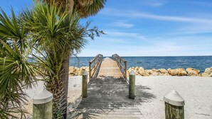 A wooden pier leading to a beach with a palm tree on the left and a rocky shoreline. - Plage d'Amour "Beach of Love" (Port Saint Joe)