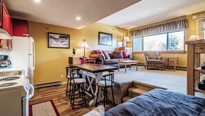 A compact living space with a kitchenette, a dining area with stools, a sofa, and a chair. - Studio Cascades Sleeps 3 (Newry)