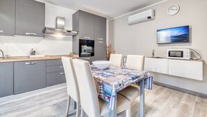 A modern kitchen with grey cabinets, a built-in oven, and a microwave on a white countertop. - Merlo C - town center & private parking (Ceriale)