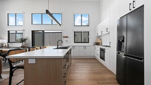 Una cocina moderna con una isla central, armarios blancos y un refrigerador negro grande.