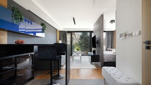A modern kitchen with a large flat-screen TV, bar stools, and a wooden dining table. - EASY RENT Apartments - AMBER 10 (Lublin)