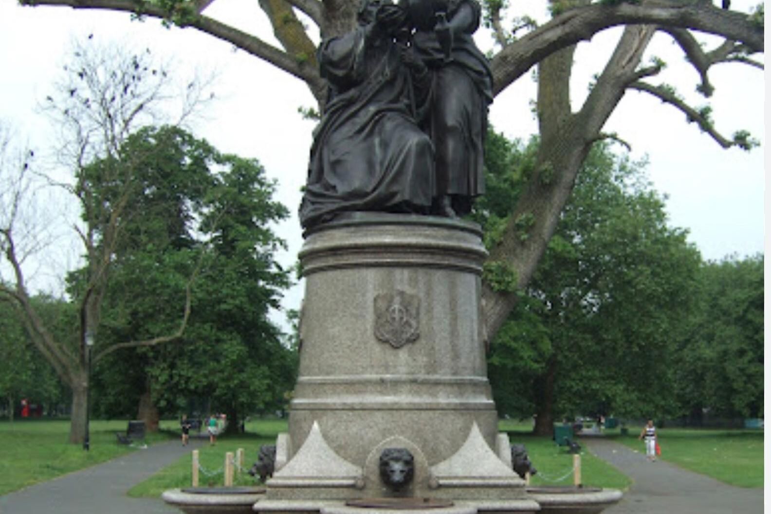 Una statua raffigurante una donna e un bambino su un piedistallo in un parco.