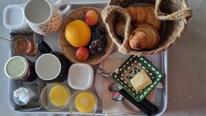 Bandeja de desayuno con cruasanes, frutas, miel, mermelada y mantequilla.