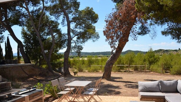 An outdoor patio with a grill, seating area, and a view of the countryside. - Large Gîte 2 people (LEZIGNAN CORBIERES)