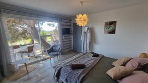 Un dormitorio moderno con cama, una silla, un televisor y vistas al exterior.