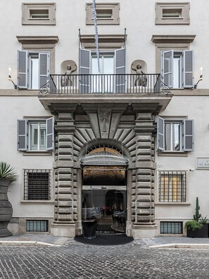 A building with a central entrance, multiple windows with shutters, and a balcony with railings. - ROMEO Roma (Rome)
