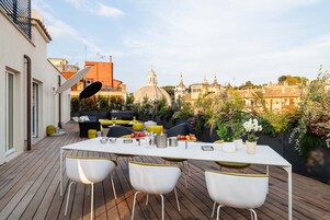 Una terraza en la azotea con mesa, sillas y vistas a un edificio histórico.
