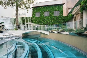 Una piscina con bordo in vetro, circondata da lettini e una ringhiera in vetro.