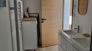 Kompakti keittiö, jossa on sisäänrakennettu pesuallas, valkoinen jääkaappi ja puuovi.