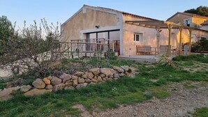 A rustic building with a stone wall, a wooden pergola, and a patio area. - Groupe 12 Personnes sur 3 Gîtes (LEZIGNAN CORBIERES)