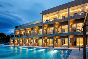 A multi-story hotel with a swimming pool, balconies with seating, and large windows. - Nueve Poolvilla And Resort (Jeju City)