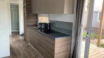 A modern kitchen with wooden cabinetry, a black countertop, and a built-in coffee maker.