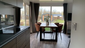 A modern kitchen with a dining area, large windows, and a view of the outdoors. - Charming Chalet 2 km. of the Efteling (Kaatsheuvel)