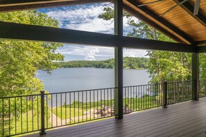 Une terrasse extérieure couverte offrant une vue sur un lac et la végétation environnante.