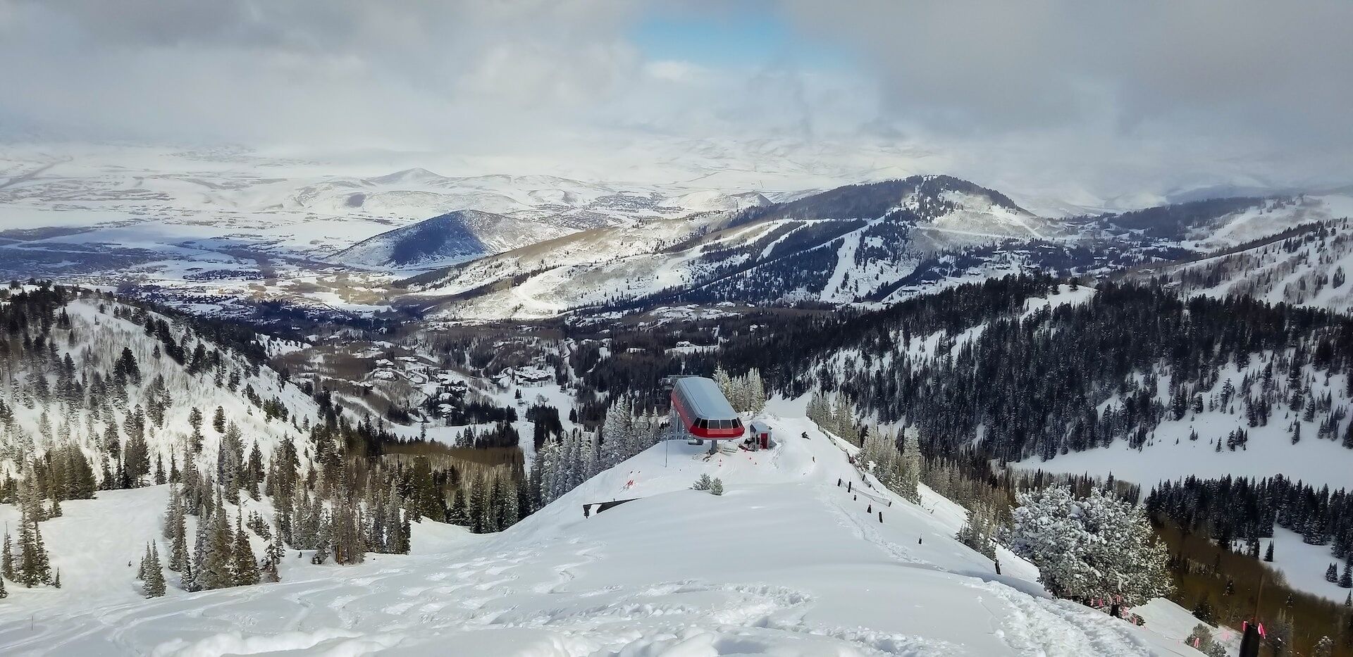 Ett snötäckt berglandskap med en skidlift och en liten röd stuga.