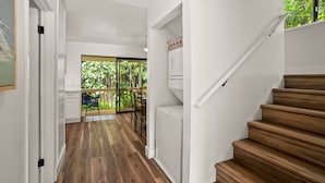A modern kitchen with a view to a balcony, wooden flooring, and a staircase.