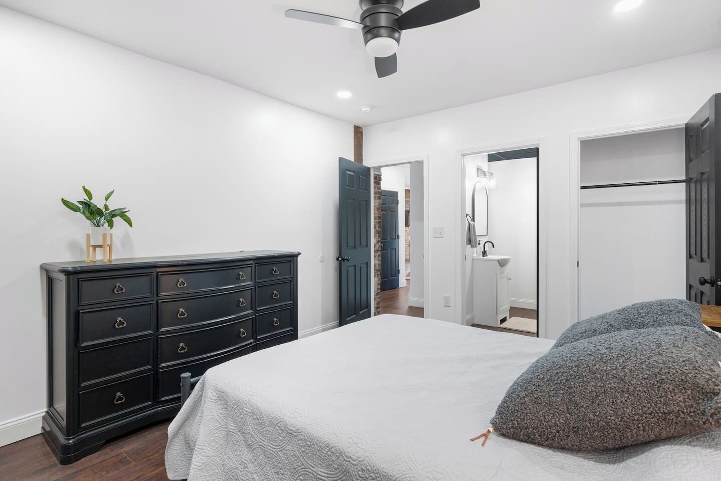 A bedroom with a bed, dresser, and a ceiling fan.