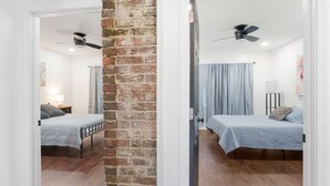 A room with two beds, a brick wall, and a ceiling fan.