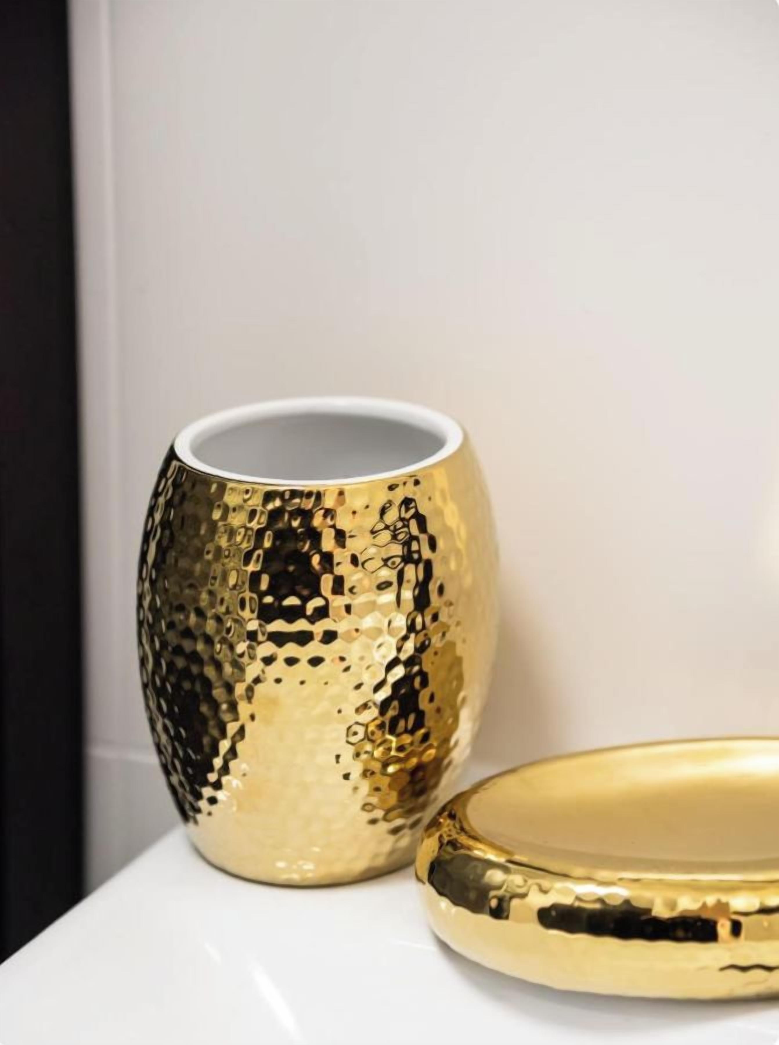 A gold-colored, textured object with a white interior, possibly a decorative item or a piece of furniture, placed on a white surface.