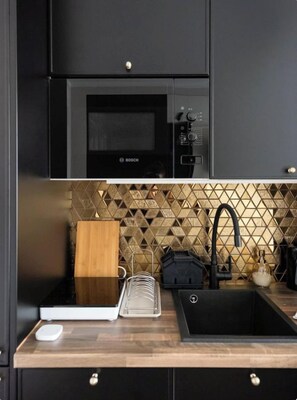 A modern kitchen with a Bosch microwave, a black sink, and a wooden cutting board. - SuperApart Nowy Służewiec 21 (Warsaw)