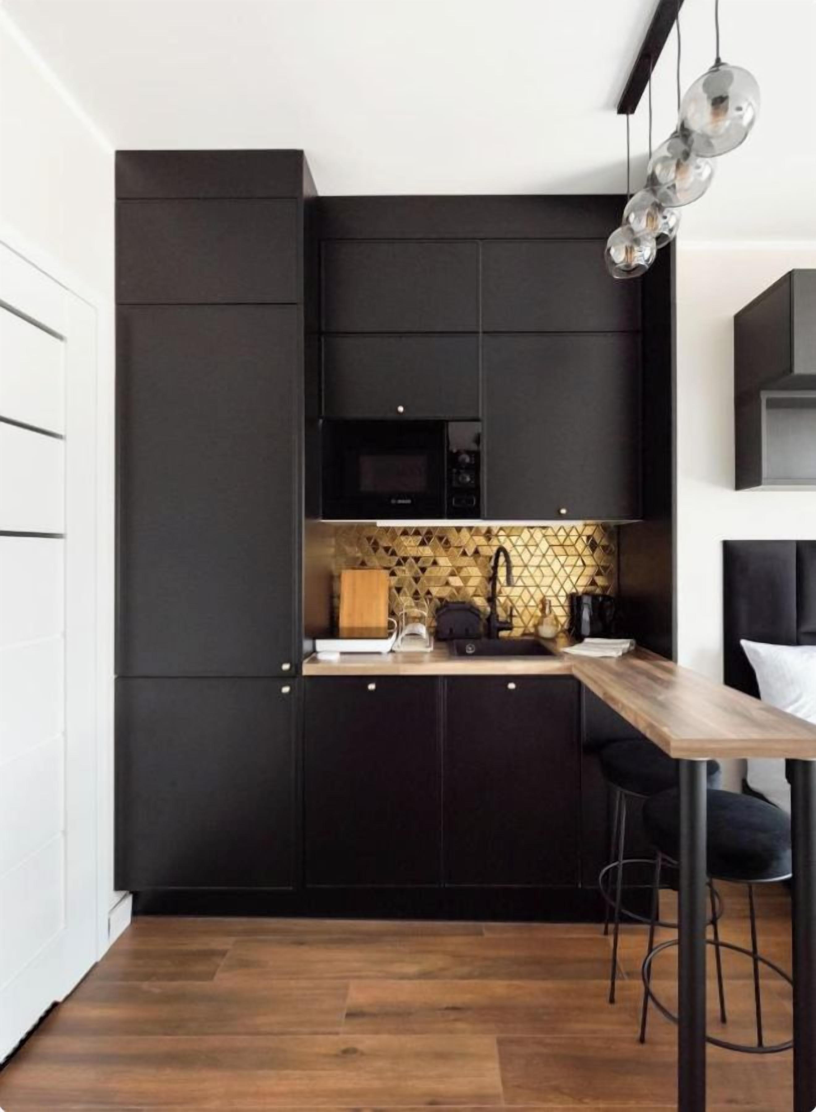 A modern kitchen with dark cabinetry, a wooden countertop, and a hanging light fixture.