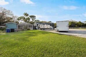 A grassy area with a large RV and a white trailer. - Cozy & Coastal Fort Pierce Pool home (Fort Pierce)