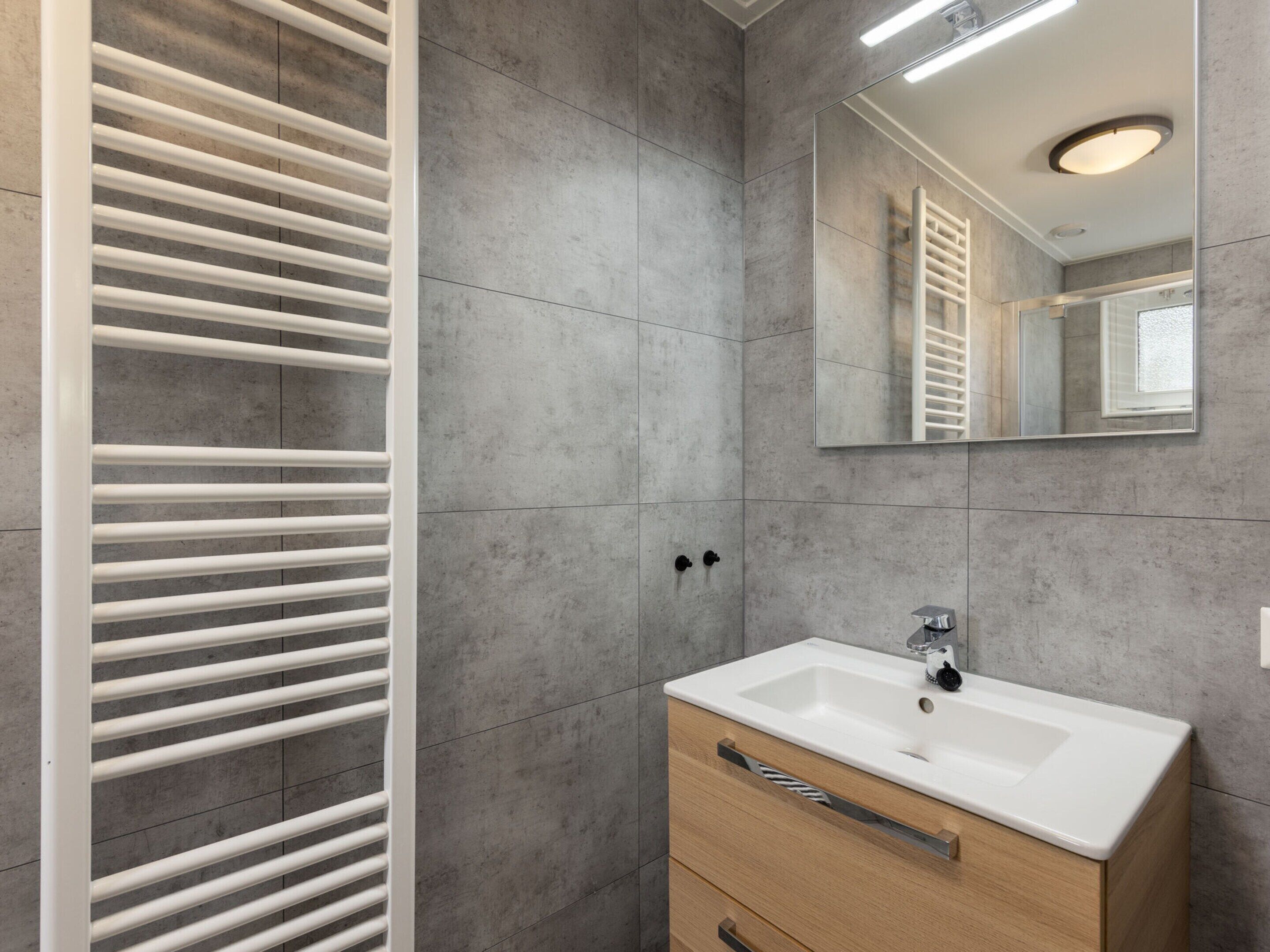 A modern bathroom with a white vanity, a mirror, and a towel rack.