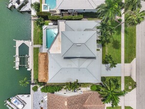Vue aérienne d’un complexe hôtelier doté d’une piscine, d’un quai et d’une structure à toit de chaume.