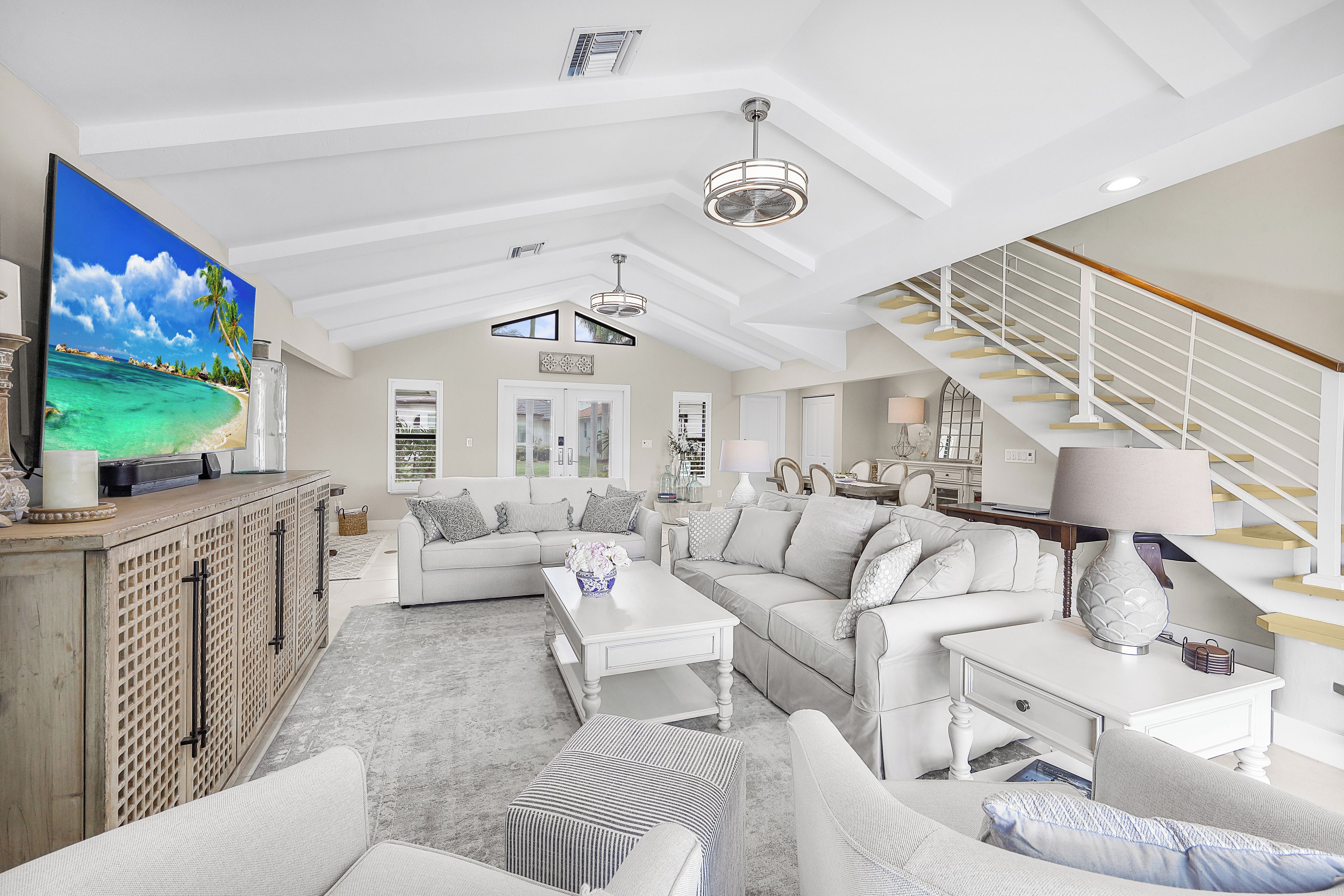 A spacious living room with a large flat-screen TV, a staircase, and a cozy seating area.