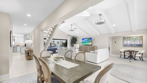 Een ruime woonkamer met een eettafel, stoelen, een bank en een televisie.