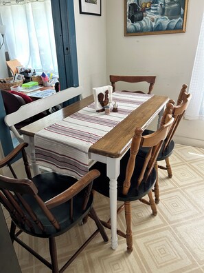 A dining table with a striped tablecloth, surrounded by wooden chairs with cushioned seats.