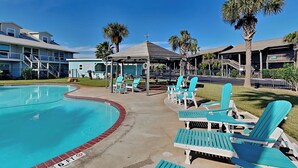 A swimming pool with lounge chairs and a covered seating area.