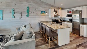 A modern kitchen with a central island, white cabinetry, and a wooden floor.