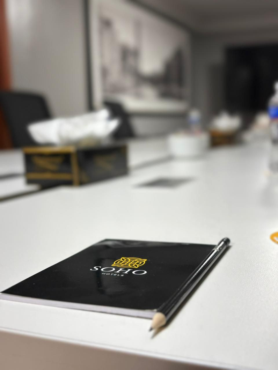 A tablet with the logo 'SOHO HOTELS' on a white table in a room with a blurred background.