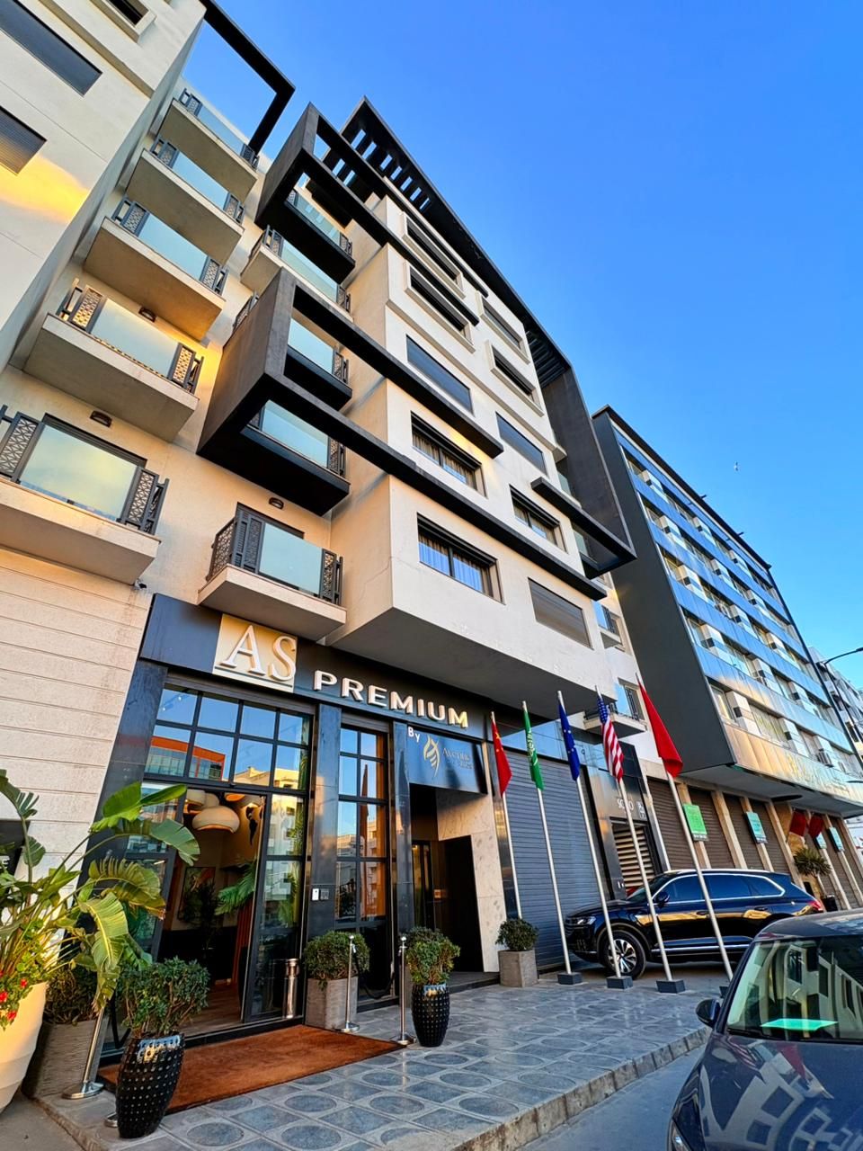 A multi-story hotel with a modern facade, a prominent 'AS PREMIUM' sign, and flags outside.