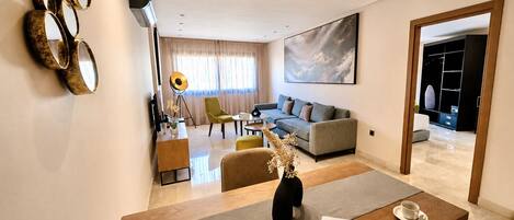 Una sala de estar moderna con un sofá, una mesa de centro y un comedor con una computadora portátil y una taza.