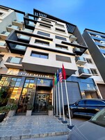 Un hotel de varios pisos con balcones, un cartel llamativo que dice 'Premium' y banderas.