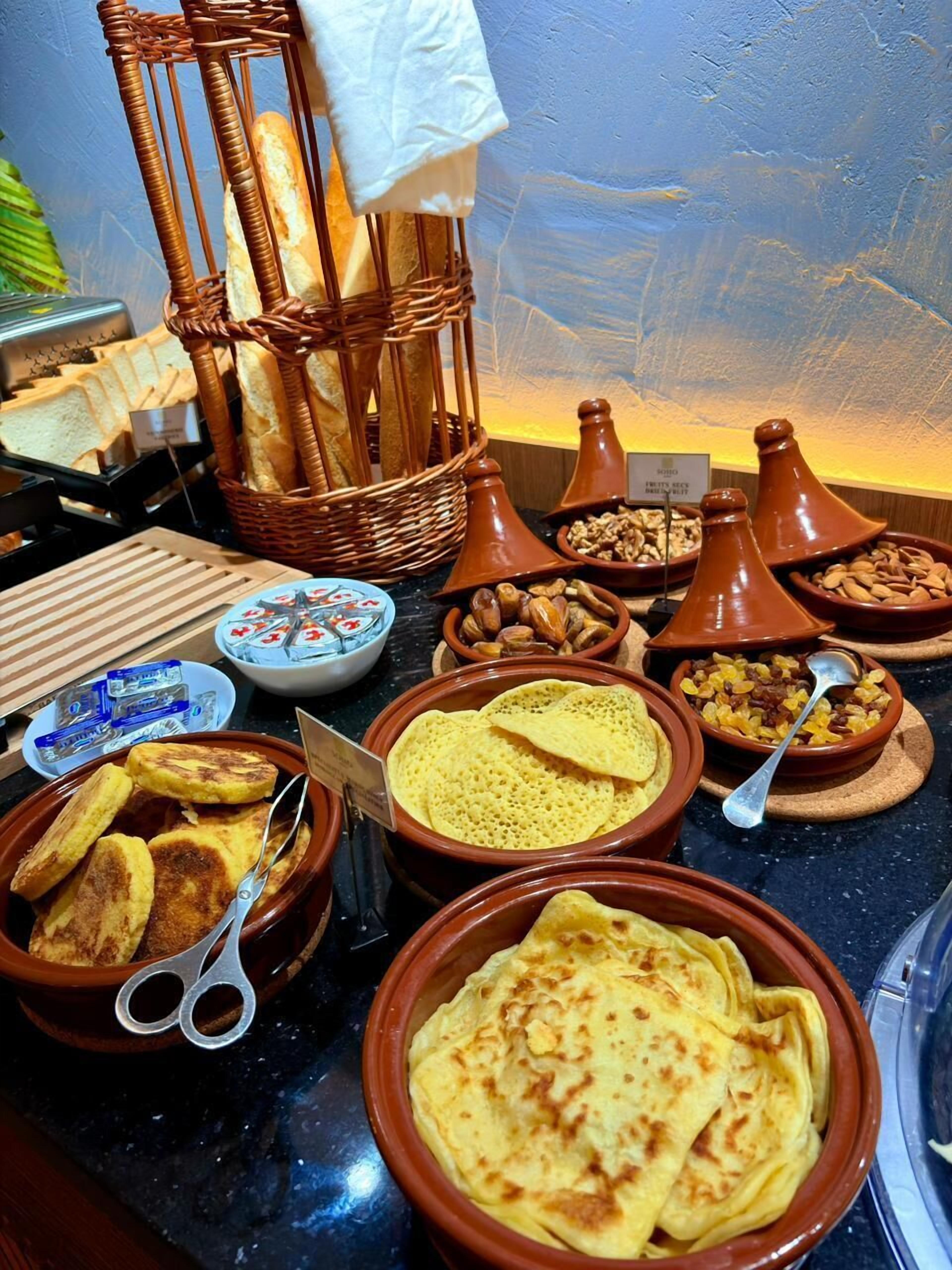 A buffet with various food items including bread, pastries, and dishes in traditional clay pots.