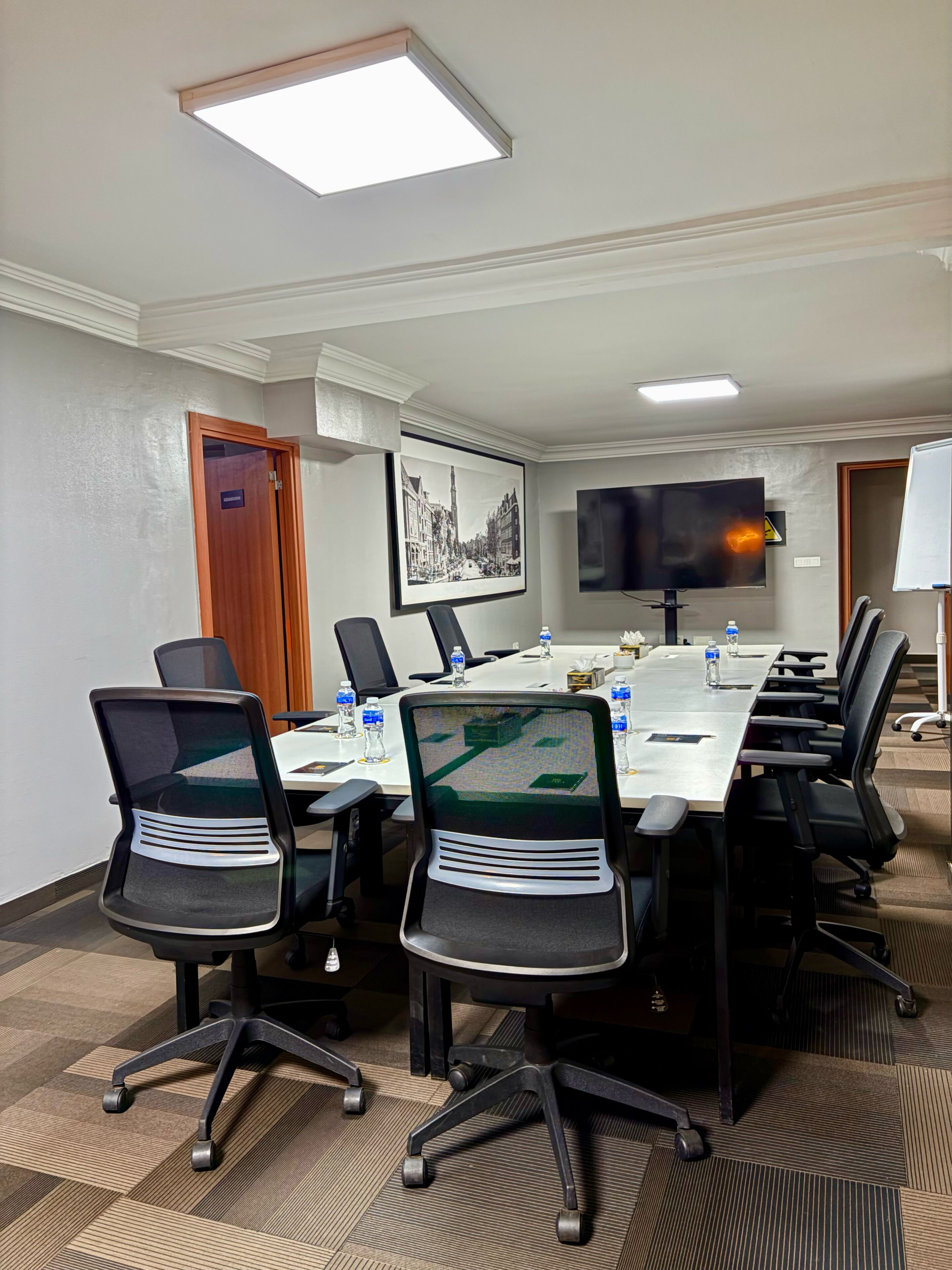 A conference room with a long table, chairs, a TV, and a framed picture on the wall.