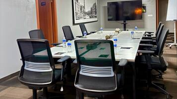 A conference room with a long table, chairs, a TV, and a framed picture on the wall.