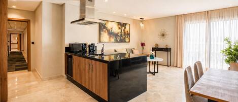 A modern kitchen with a central island, a dining area with a table and chairs, and a staircase leading to another level.
