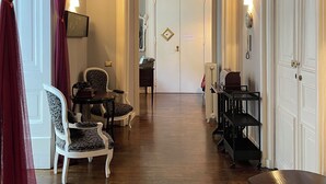 A hallway with a wooden floor, a white door at the end, and a red curtain on the left. - Anima Partenopea (Naples)