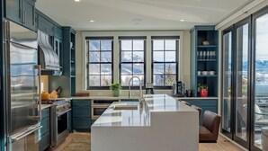 A modern kitchen with a central island, large windows, and a view of mountains. - Academy Place | Glacier Lily Penthouse (Crested Butte)