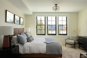 A bedroom with a bed, a chair, a dresser, and a window with a view. - Yarrow at Academy Place (Crested Butte)