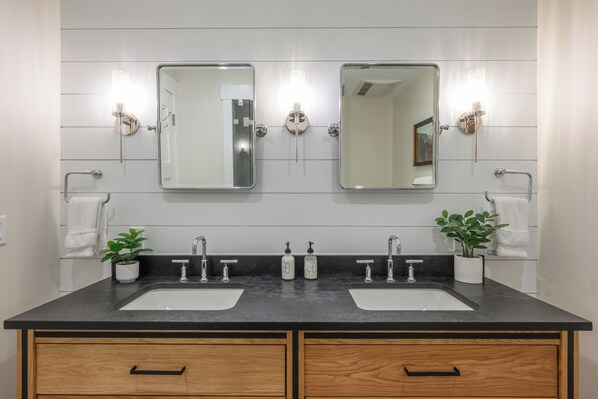 A bathroom with two sinks, two mirrors, and two wall-mounted light fixtures.