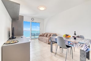 A modern kitchen with a dining area, a sofa, and a table set for a meal. - Lanterne Luxury Apartments (Borghetto Santo Spirito)